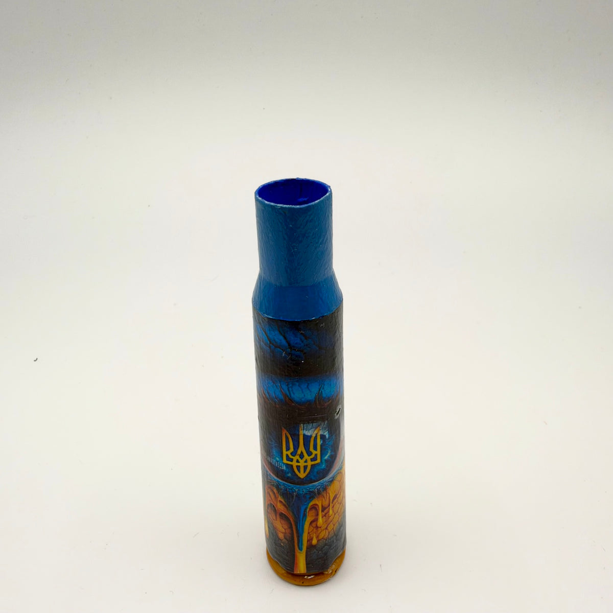 Decorated casing with a blue neck and gold base, featuring a blue eye with a yellow Ukrainian trident at its centre and flowing orange and gold patterns below.