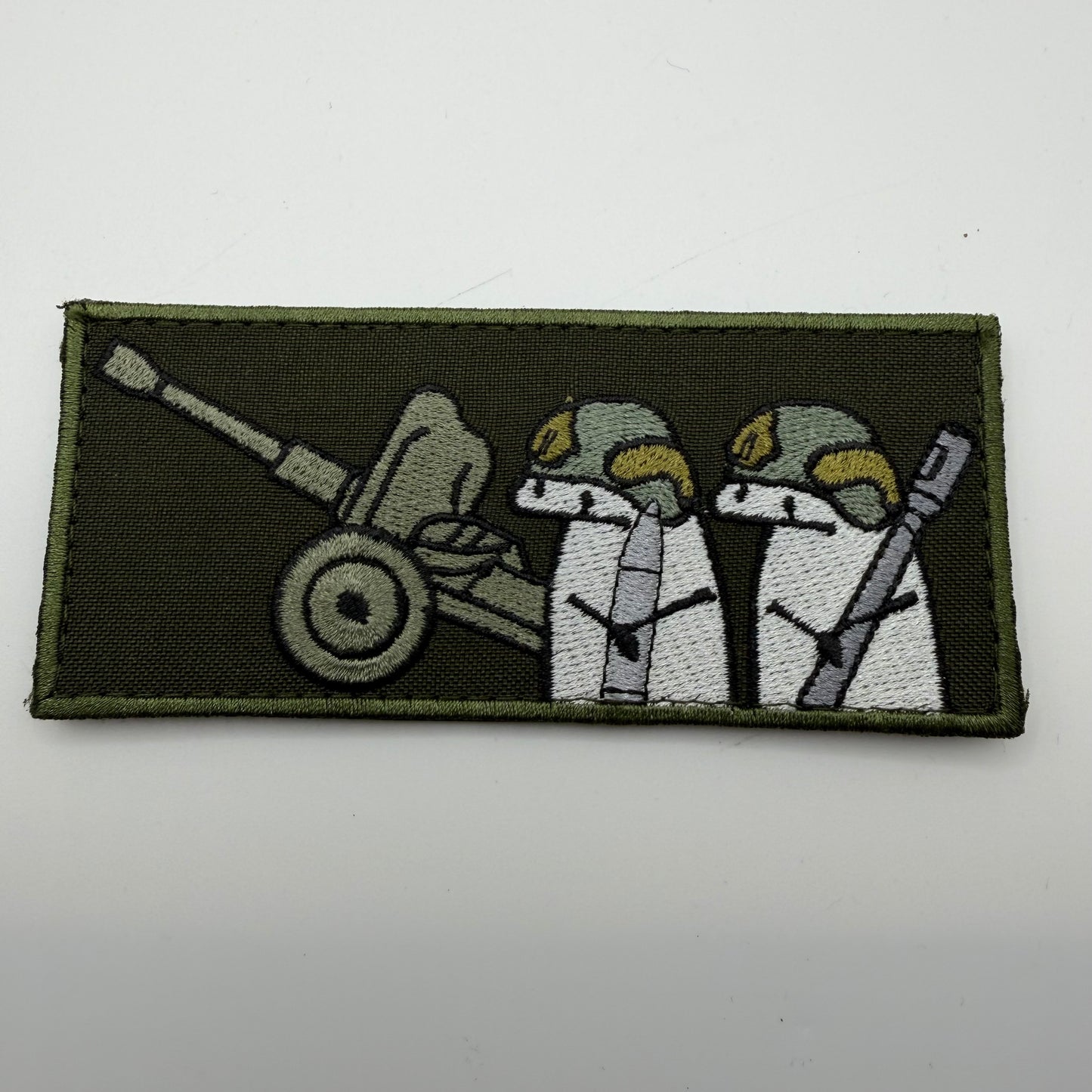 Patch with two characters and a cannon on a green background