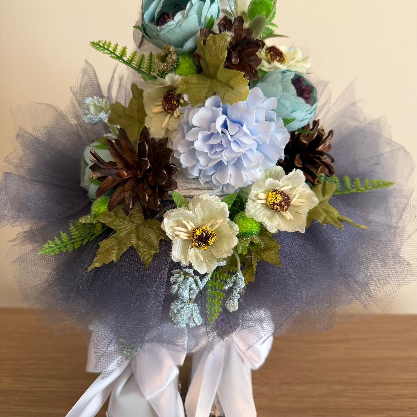 Bouquet of artificial flowers with tulle and ribbons on a wooden surface