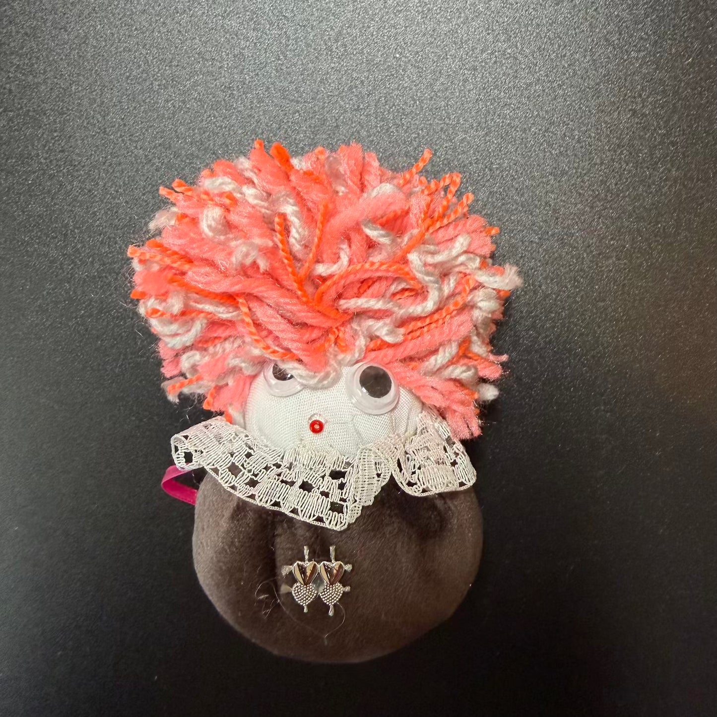 Decorative item with pink and orange hair on a dark background