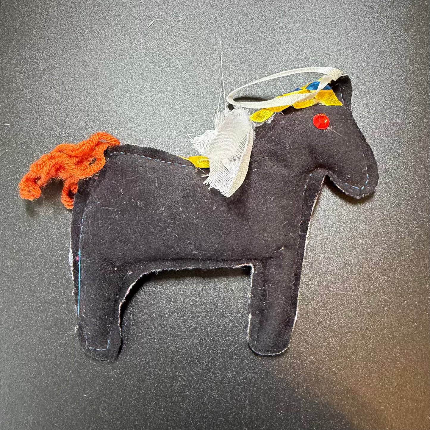 Black horse figurine with colorful mane and decorative headband on a gray background