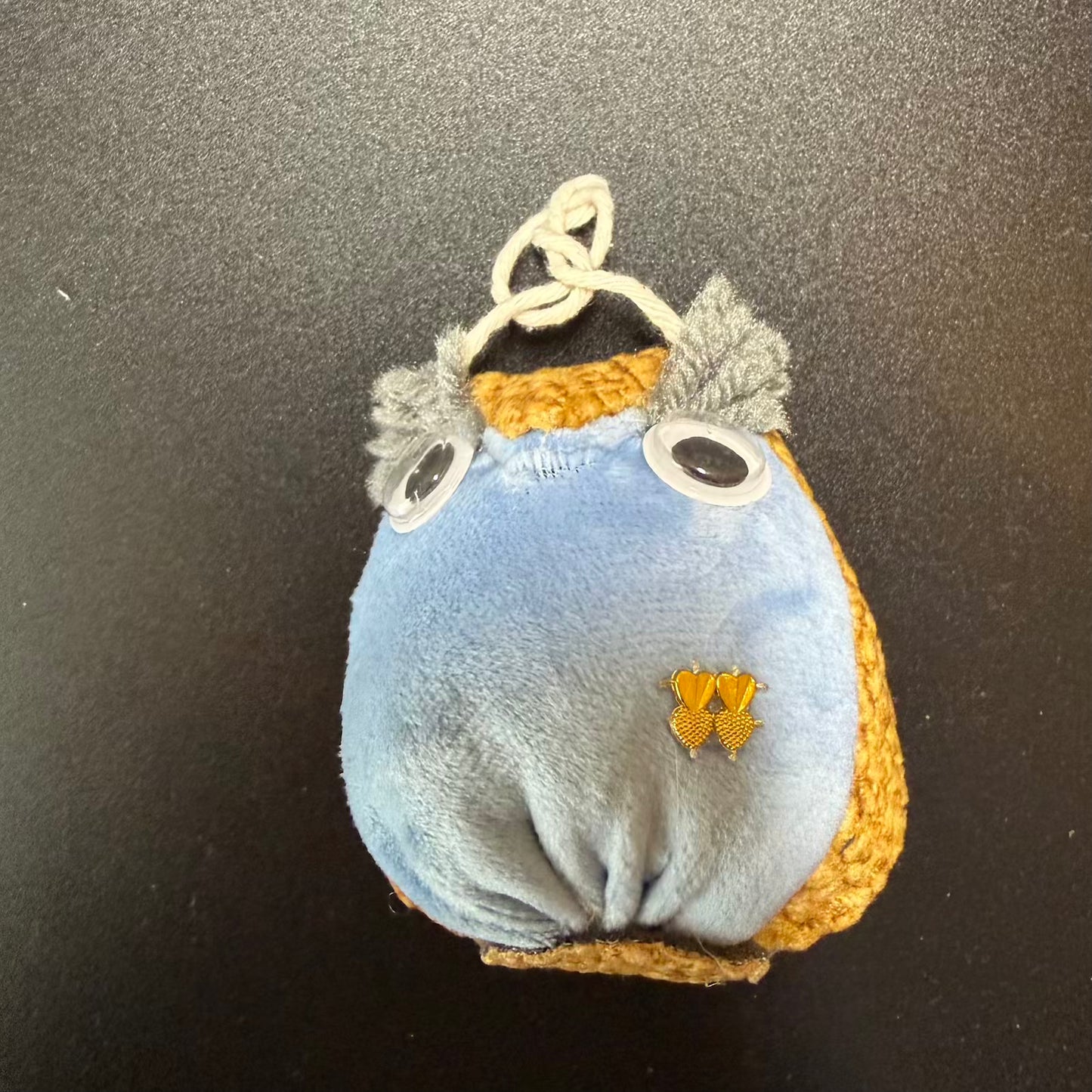 Small blue plush toy with orange accents on a black background