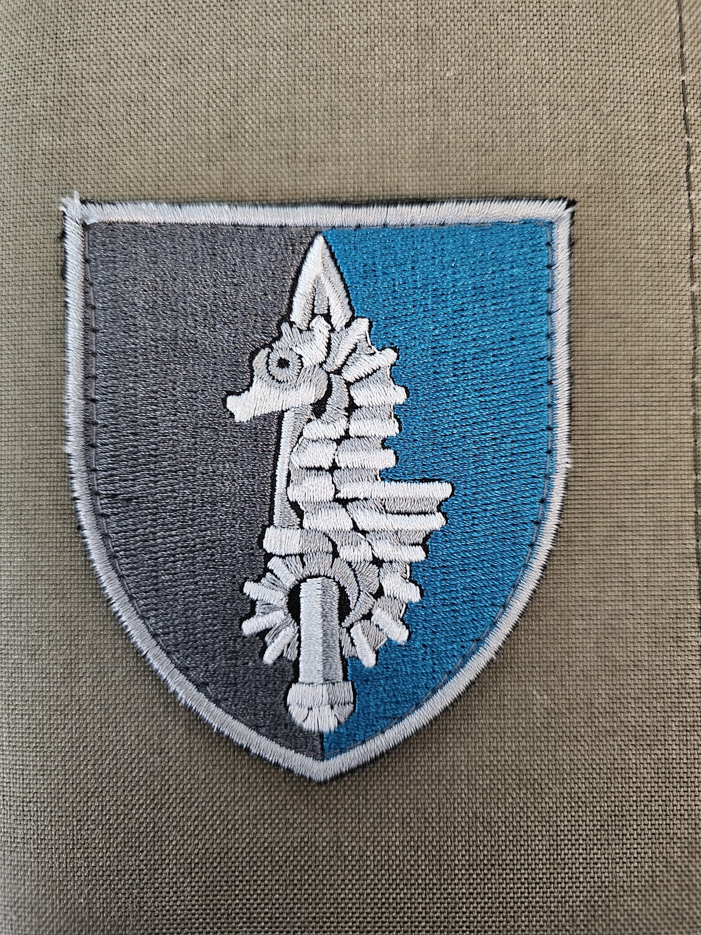 Blue and Grey fabric patch featuring a sea horse intertwined with a sword.
