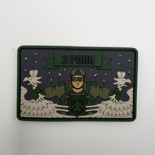 Rectangular Khartiia anniversary patch with a green border, depicting a Ukrainian soldier pulling apart a crowned double-headed eagle beneath the Ukrainian text “2 РОКИ,” meaning “2 Years.”