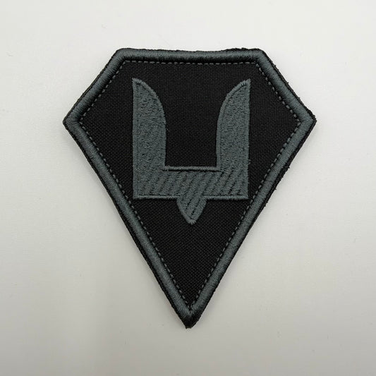 Ukrainian Special Operations Forces patch with a grey embroidered bident of Prince Sviatoslav on black fabric, framed by an angular diamond-shaped grey border.