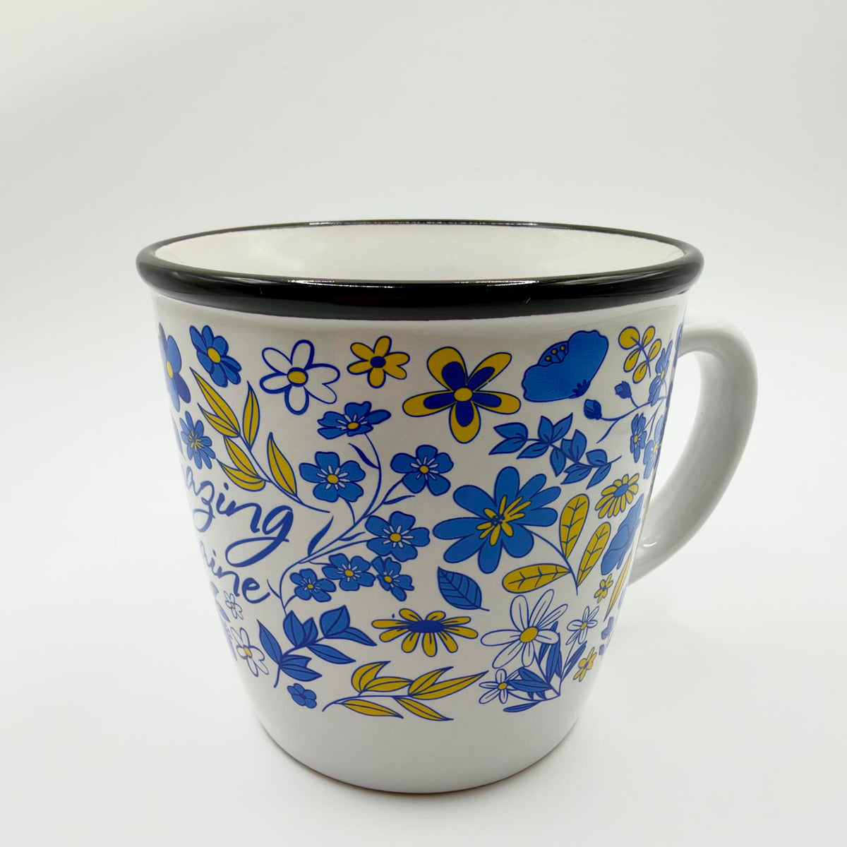 Side view of the Amazing Ukraine mug showing blue and yellow floral decoration, a white curved handle and contrasting black rim.