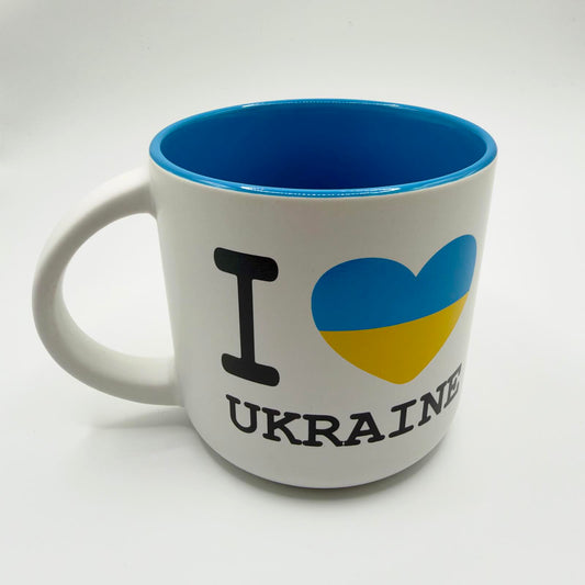 White “I Love Ukraine” mug with black lettering, a blue and yellow heart, bright blue interior and rim, and a white curved handle.