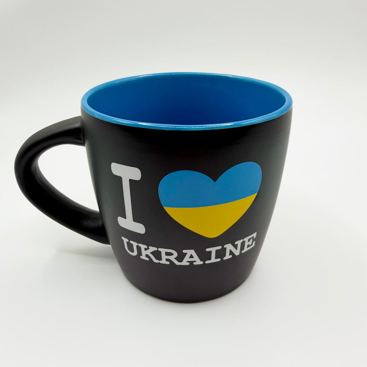 Black mug with a bright blue interior and rim, white “I love Ukraine” lettering and a heart in the blue and yellow colours of the Ukrainian flag.