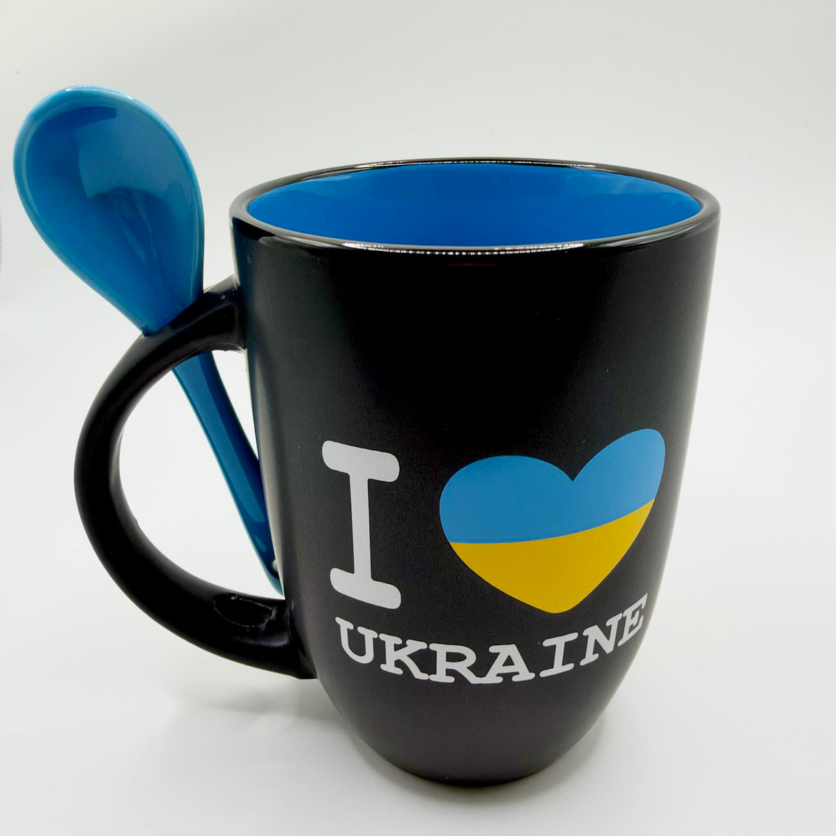 Black “I Love Ukraine” mug with a blue and yellow heart, bright blue interior and matching blue spoon slotted into the handle.
