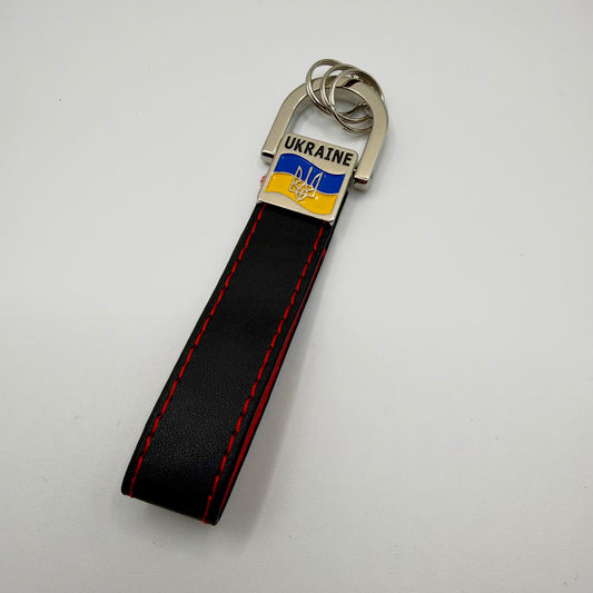 Black strap keyring with red stitching, silver-tone rings and a badge featuring UKRAINE lettering, a blue and yellow flag and a Tryzub.