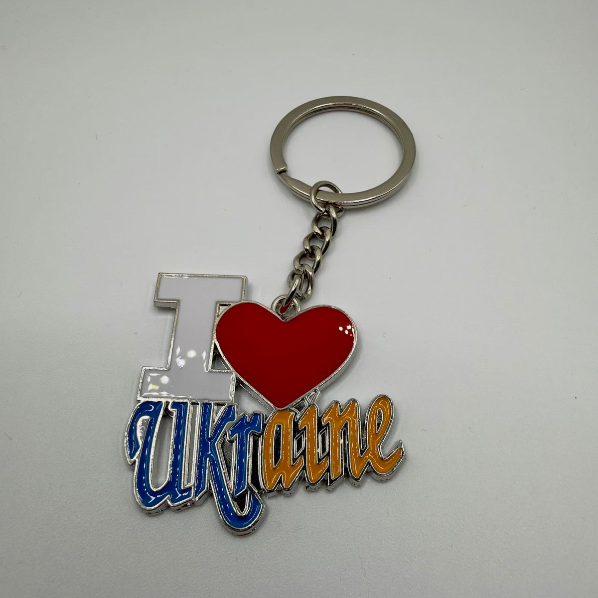 “I Love Ukraine” keyring with a white I, red heart, blue and yellow Ukraine lettering, silver-tone edging, short chain and split ring.