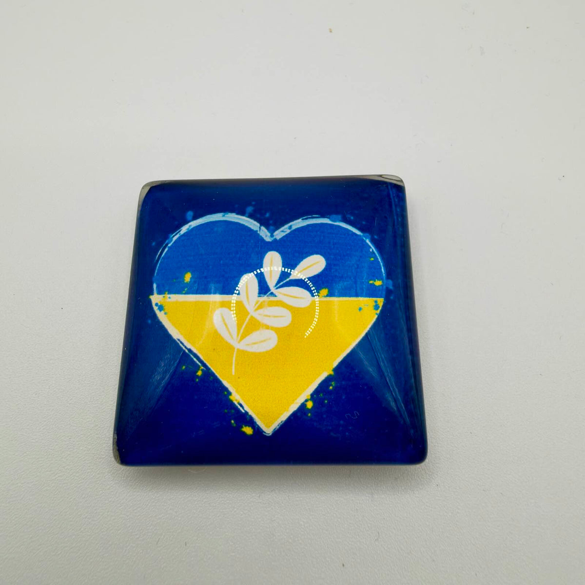 Rectangular acrylic fridge magnet with rounded corners, featuring a blue and yellow heart and white leafy sprig on a deep blue background.