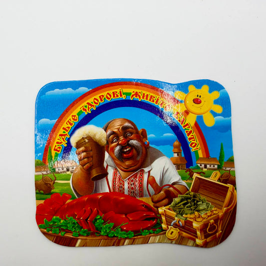Colourful Ukrainian fridge magnet showing a man raising a frothy tankard beneath a rainbow, with a red crayfish, treasure chest and a wish for health and prosperity.