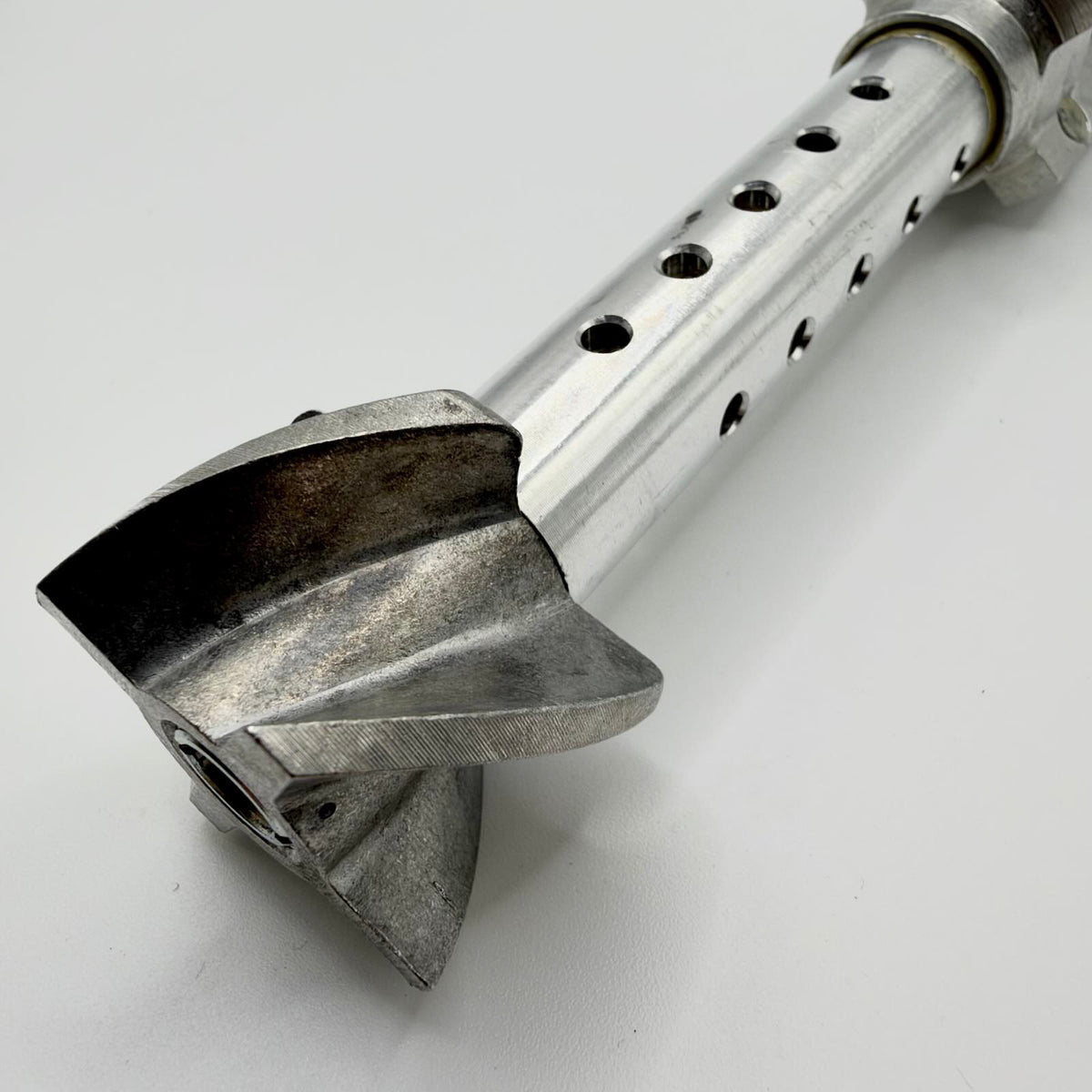 Close-up of the stabiliser’s curved rear vanes and perforated metal tube, showing surface wear and machining marks.
