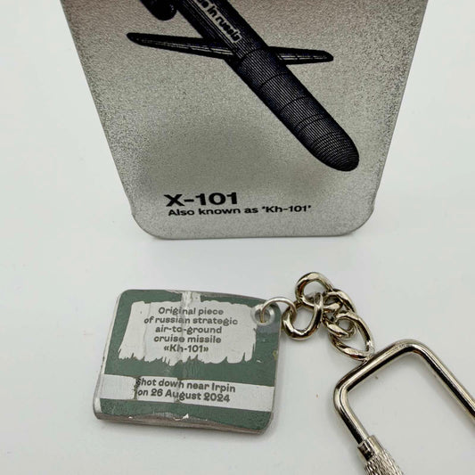 RE4WIN missile fragment keyring with an inscription identifying a Kh-101 shot down near Irpin on 26 August 2024, beside an X-101 display card.