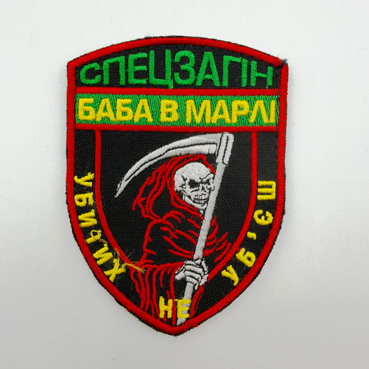 Black shield-shaped patch with red edging, a grinning skeleton in a red hood holding a white scythe, and green-and-yellow Ukrainian lettering reading “Special Detachment: Baba v Marli” and “You can’t kill the dead.”