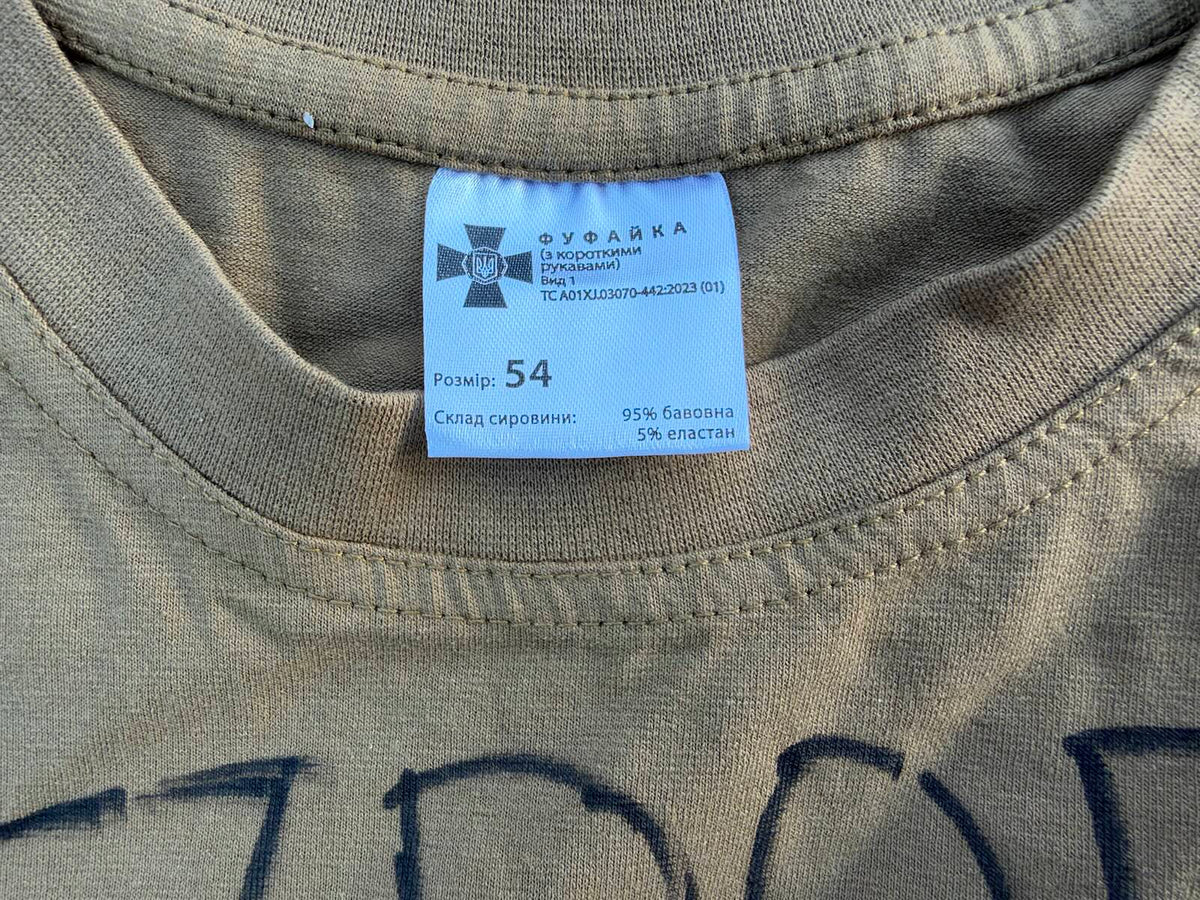 Close-up of the T-shirt’s Ukrainian clothing label showing size 54, short-sleeved Type 1 designation, and fabric composition of 95% cotton and 5% elastane.