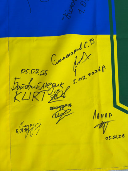 Close-up of signatures on the yellow fabric, including “Combat medic KURT” in Ukrainian and English, with dates of 5 July 2026.