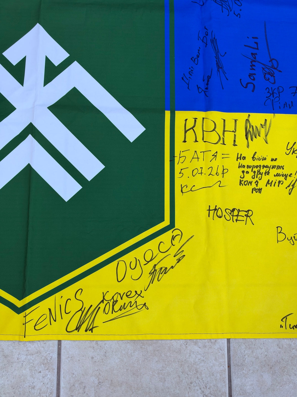 Detail of the Khartiia emblem and surrounding signatures, including Batya, HOSTER and FeNiCS, with a handwritten Ukrainian message.