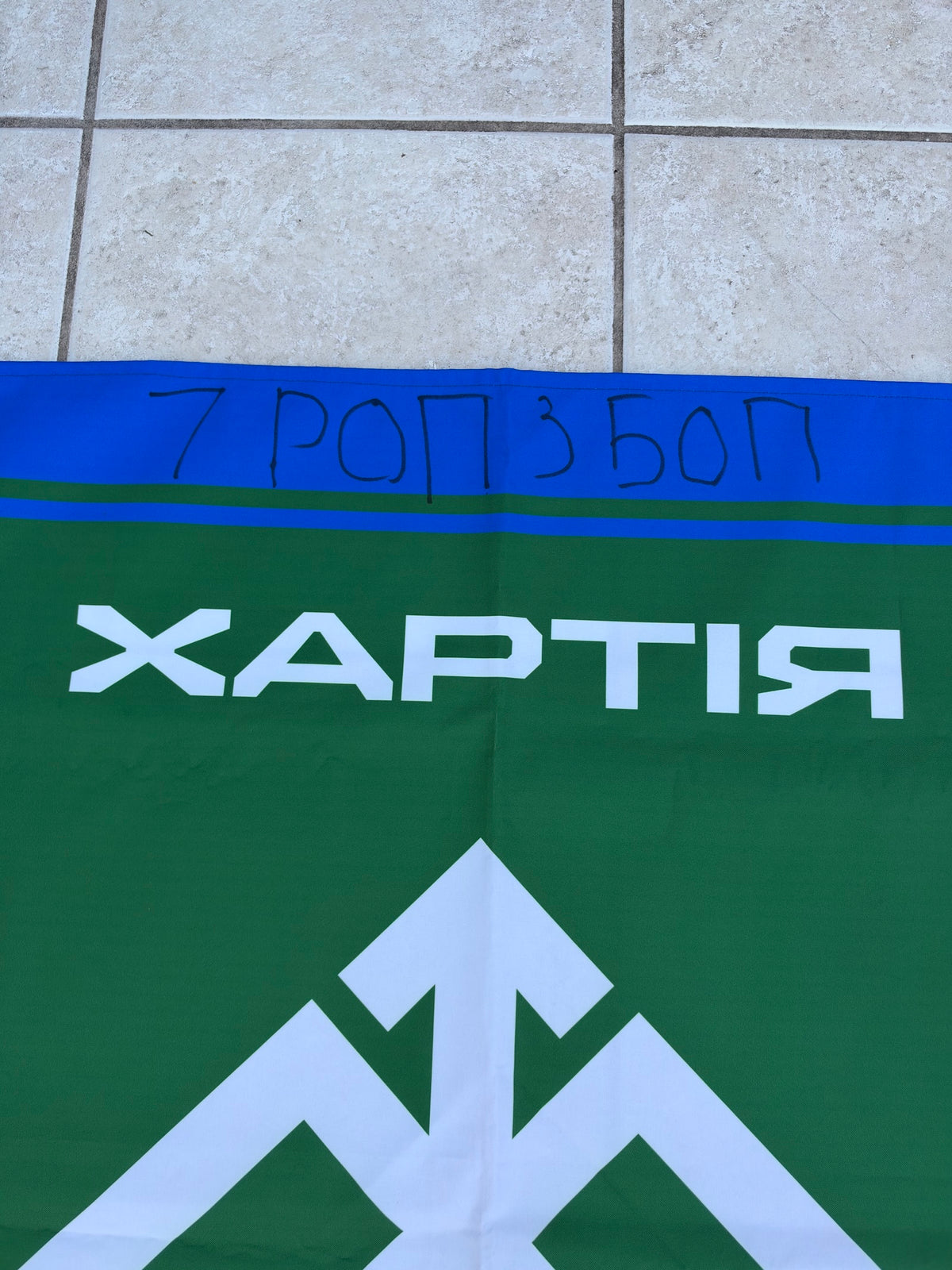 Detail of handwritten “7 РОП 3 БОП” above the printed Khartiia name and the upper part of its white emblem on a green shield.