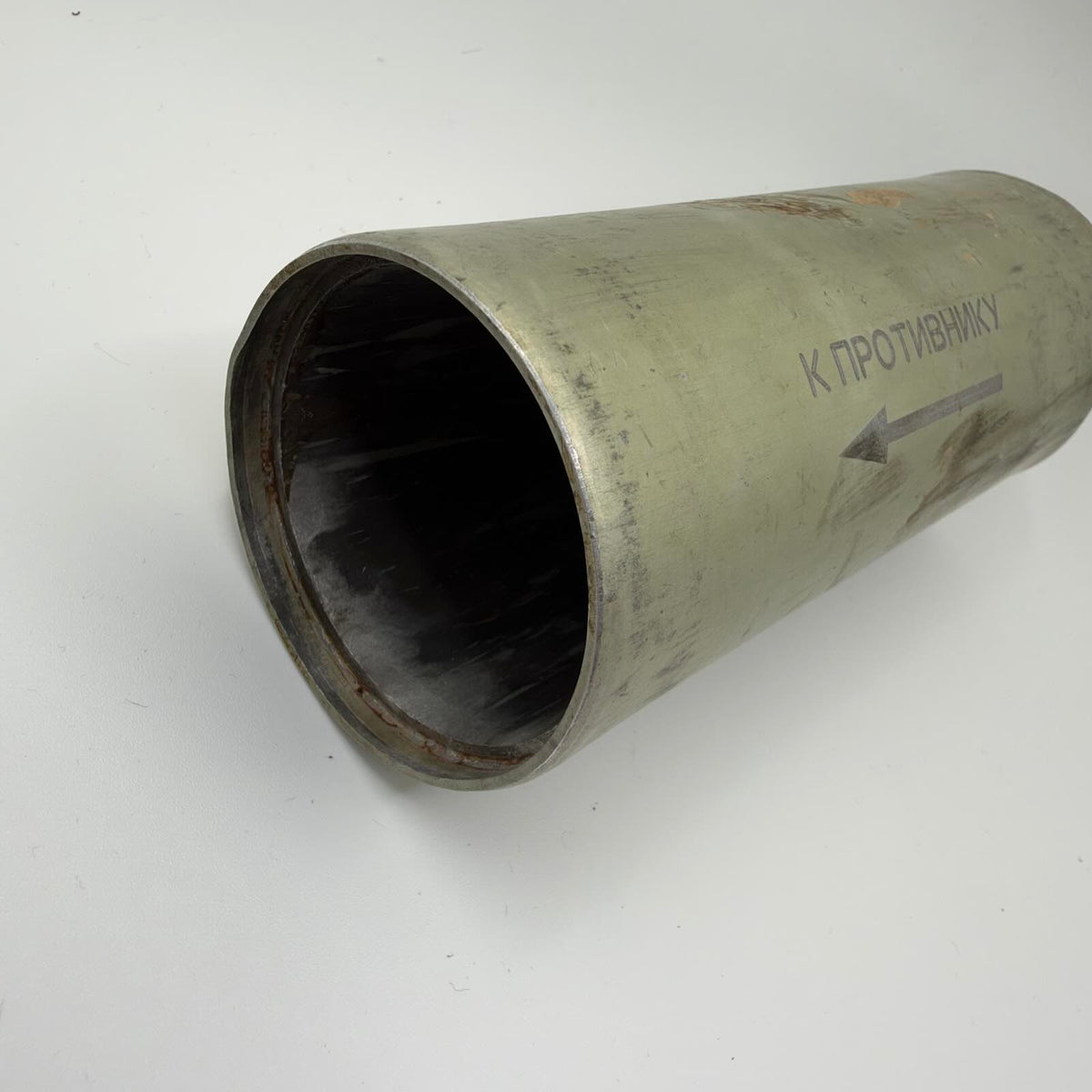 Angled view of the hollow metal cylinder showing its open end, recessed rim and Russian directional marking.