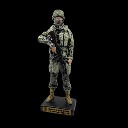 Full-length Ukrainian soldier figure on a black base, wearing green combat equipment and holding a rifle, against a black background.