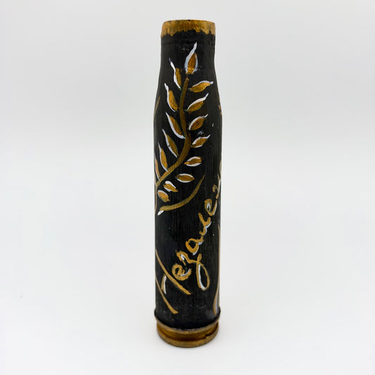 Upright shell casing hand-painted black with a curling gold leafy branch, white highlights, gold script, and gold accents around the rim and base.