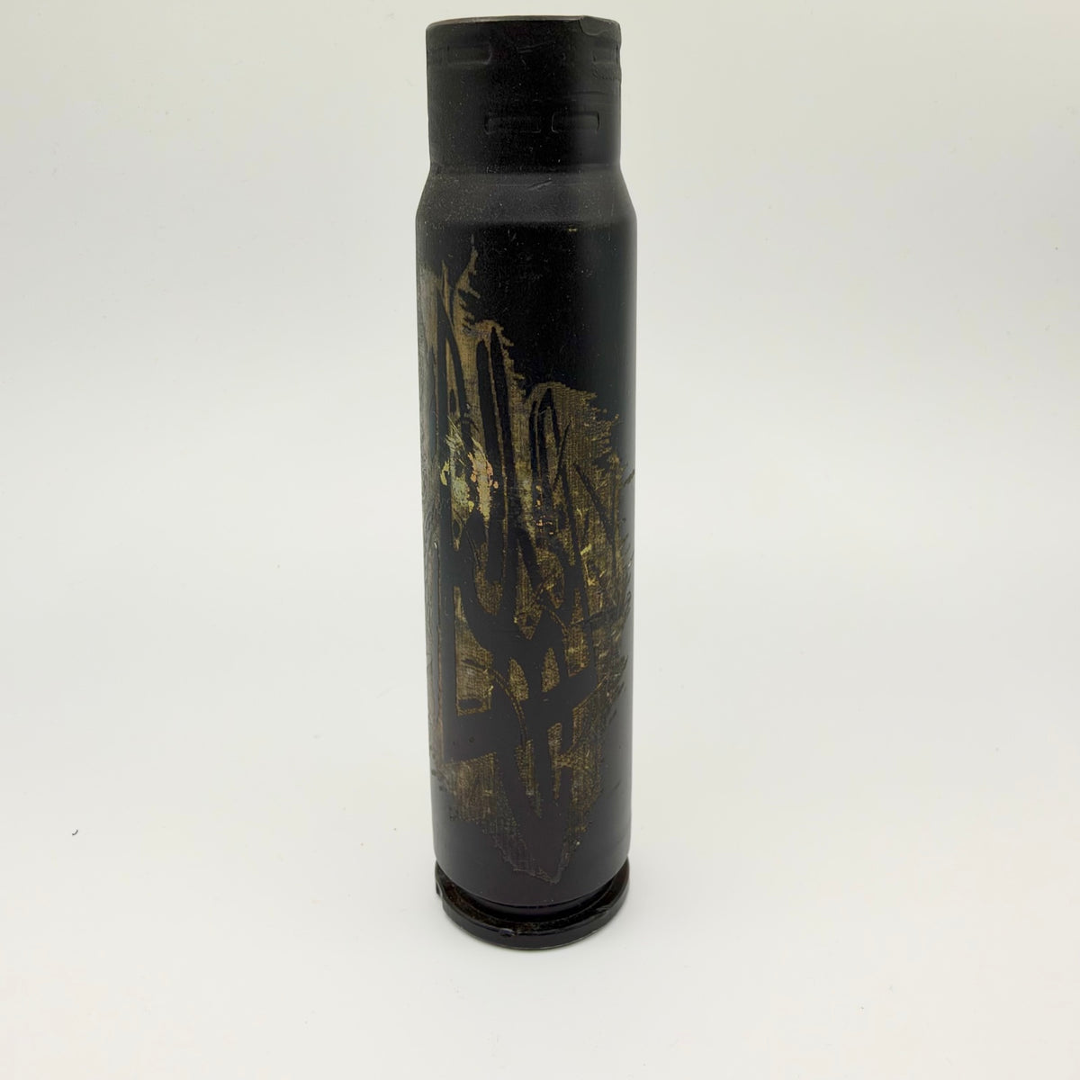 Upright black shell casing decorated with a dark Ukrainian trident against textured, distressed gold brushwork, photographed on a pale background.