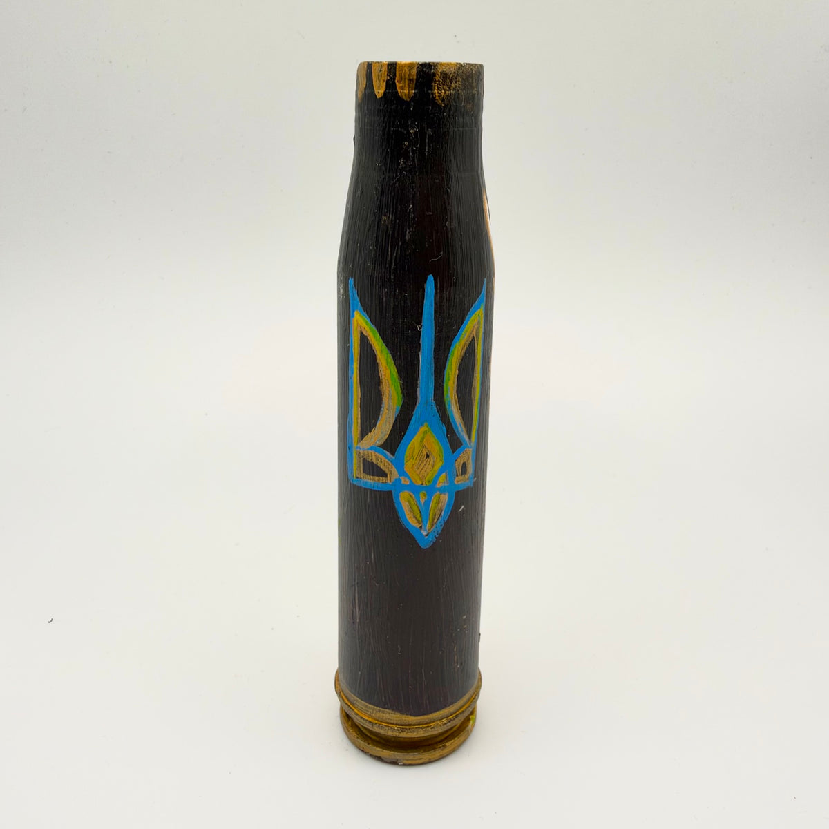 Black shell casing hand-painted with a large blue Ukrainian trident with yellow and gold detailing, plus gold accents around the top rim and base.