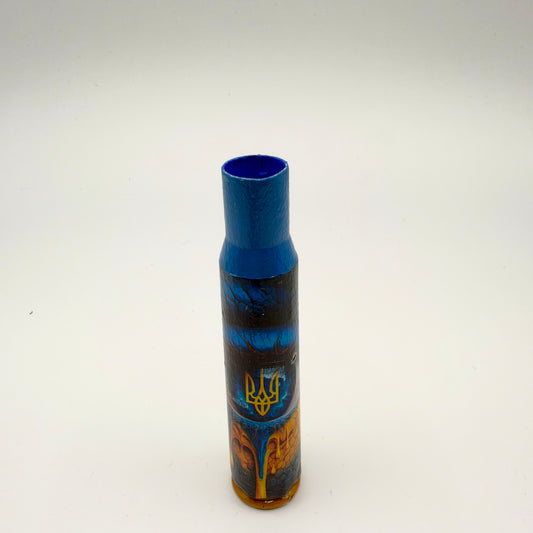 Decorated casing with a blue neck and gold base, featuring a blue eye with a yellow Ukrainian trident at its centre and flowing orange and gold patterns below.