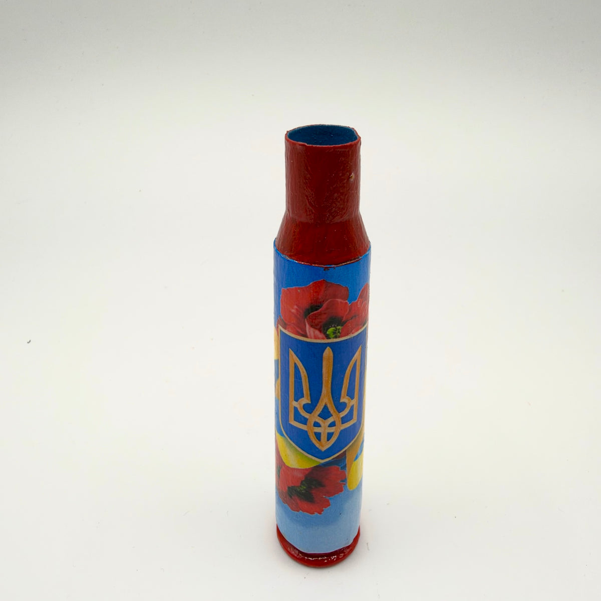 Decorated casing with a red neck and base, featuring a gold Ukrainian trident on a blue shield surrounded by red poppies and blue and yellow ribbons.