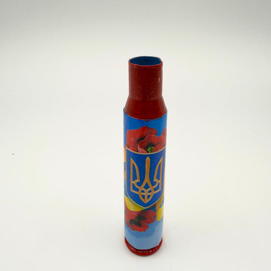Decorated casing with a red neck and base, featuring a gold Ukrainian trident on a blue shield surrounded by red poppies and blue and yellow ribbons.