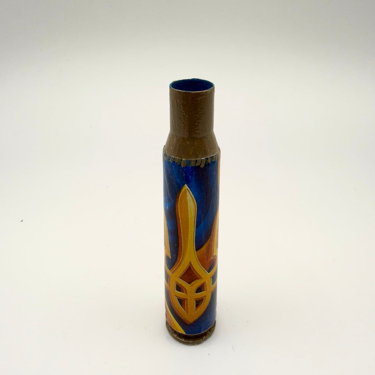 Decorated casing with a bronze-brown neck and base, featuring a large golden-yellow Ukrainian trident with orange shading against a deep blue background.