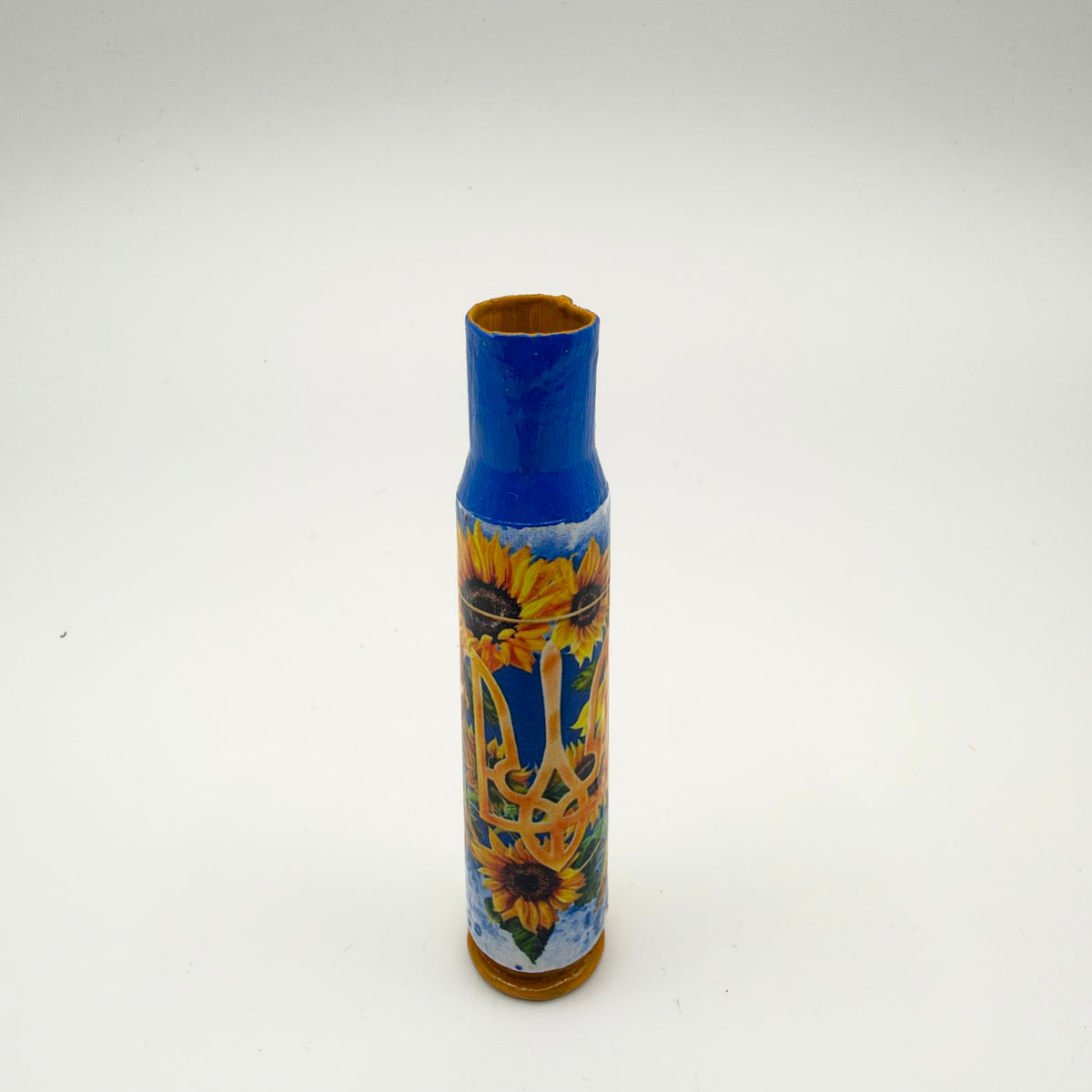 Decorated casing with a blue neck and golden-yellow base, featuring a golden Ukrainian trident surrounded by yellow sunflowers and green leaves on a blue and white background.