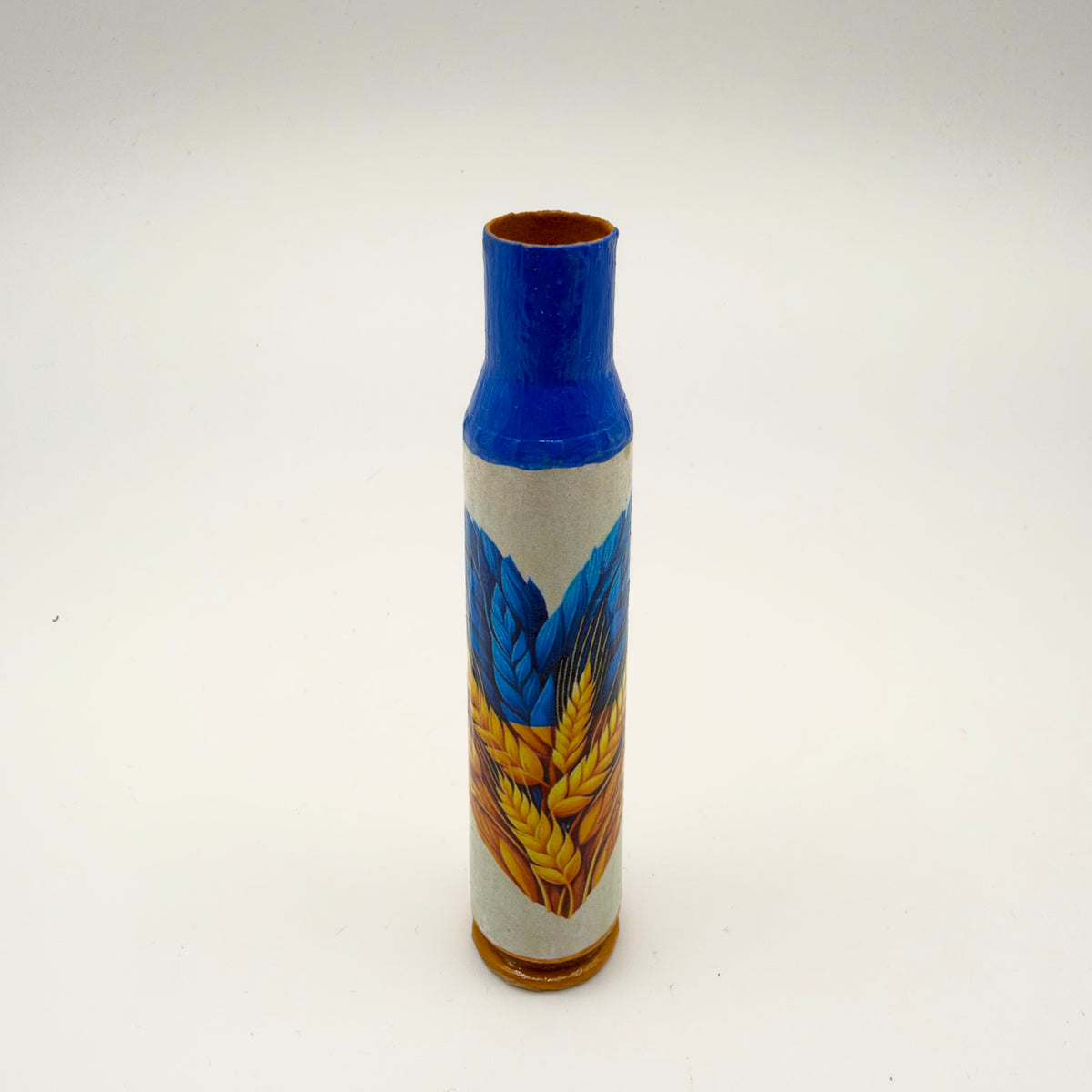 Decorated casing with a bright blue neck and golden-yellow base, featuring overlapping blue and golden wheat ears on a pale cream background.