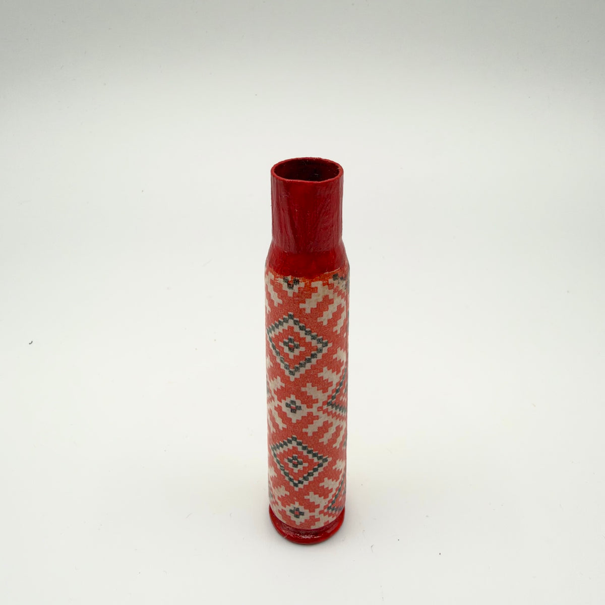 Decorated casing with a red neck and base, featuring a red, cream-white and black embroidery-style pattern of repeating diamonds, crosses and stepped geometric shapes.