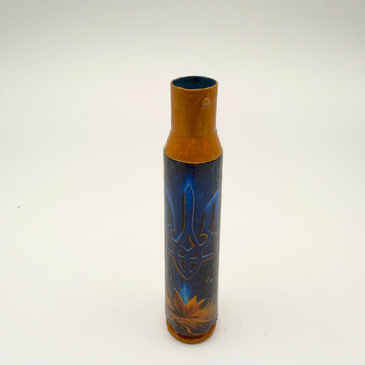 Decorated casing with a golden-orange neck and base, featuring a blue Ukrainian trident with fine gold outlines on dark navy, above an orange-gold botanical flourish.