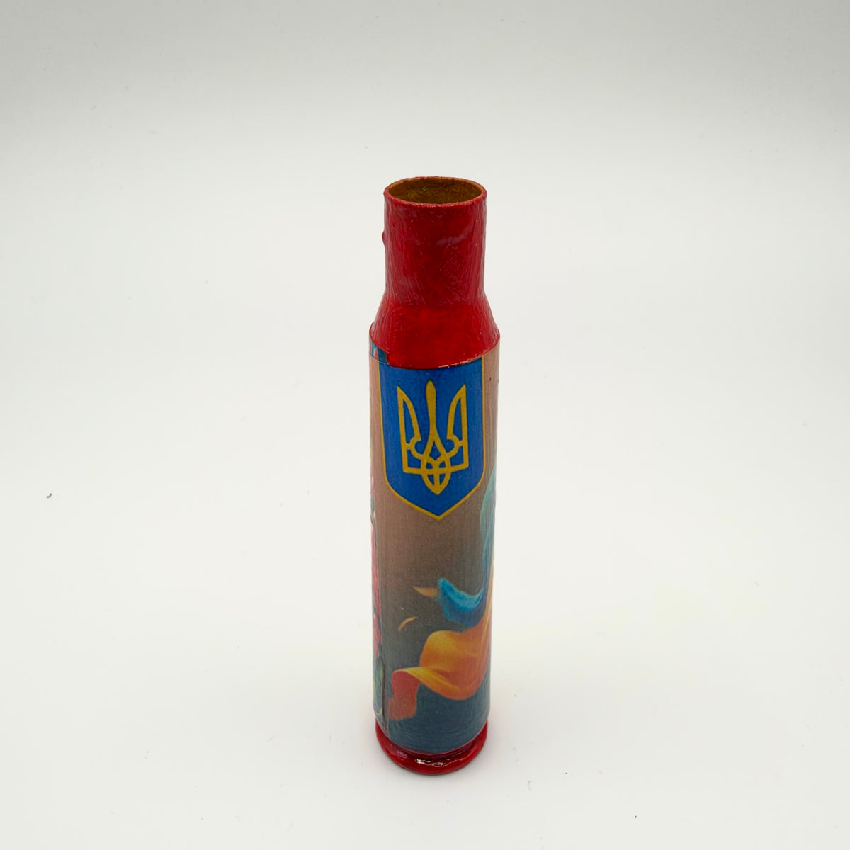 Decorated casing with a red neck and base, featuring a yellow Ukrainian trident on a blue shield above flowing blue and yellow-orange shapes on a muted background.
