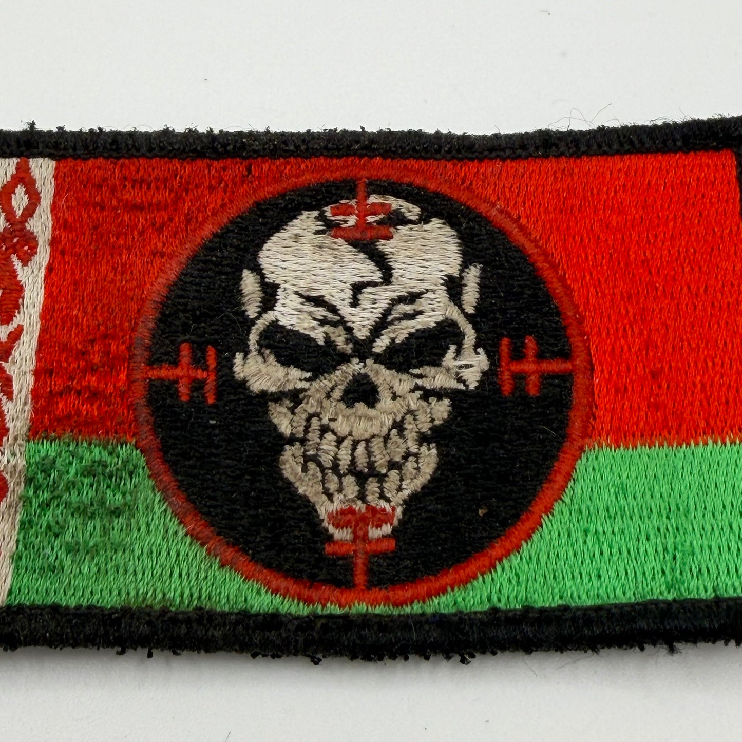 Rectangular Velcro patch showing Red and green background with a skull in crosshairs