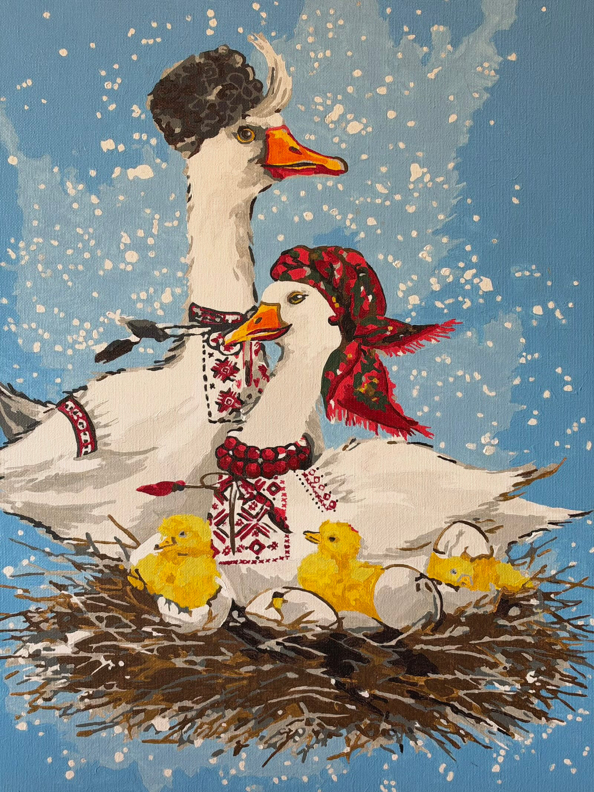 Oil painting of two white geese in Ukrainian folk-inspired clothing beside yellow goslings hatching in a twig nest. One goose wears a dark hat and embroidered shirt; the other wears a red floral headscarf, red beads and embroidery. A gosling peeks from beneath an eggshell against a pale blue, white-speckled background.