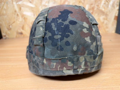 Rear view of the used composite helmet, showing the seams, retaining band and wear on its Flecktarn camouflage cover.