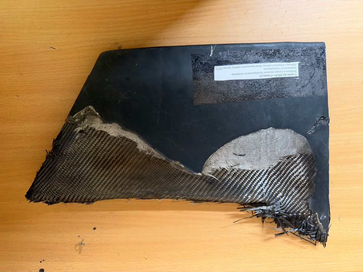 Reverse of the recovered Geran-2 lower stabiliser, showing the provenance label, damaged composite structure and a large exposed fabric section.