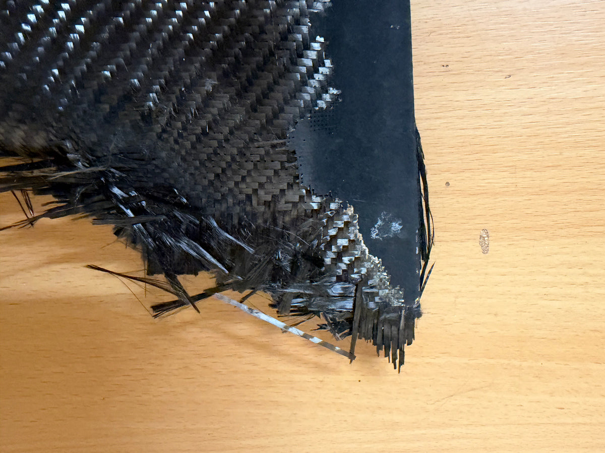 Close-up of the stabiliser’s severely frayed edge, showing broken woven composite material and numerous loose fibres.