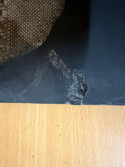 Close-up of surface damage and exposed composite reinforcement on the black skin of the Geran-2 drone stabiliser.