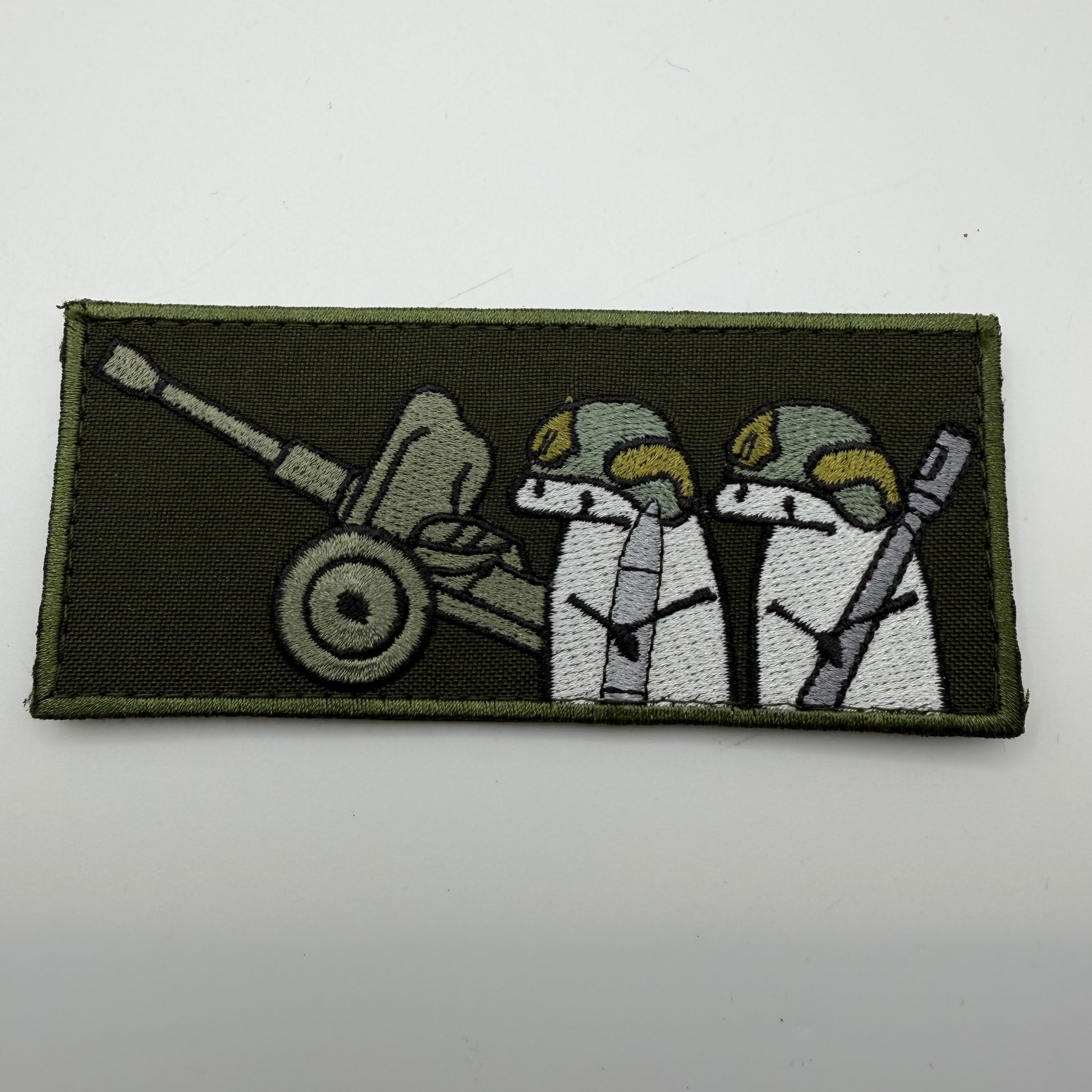 Patch with two characters and a cannon on a green background