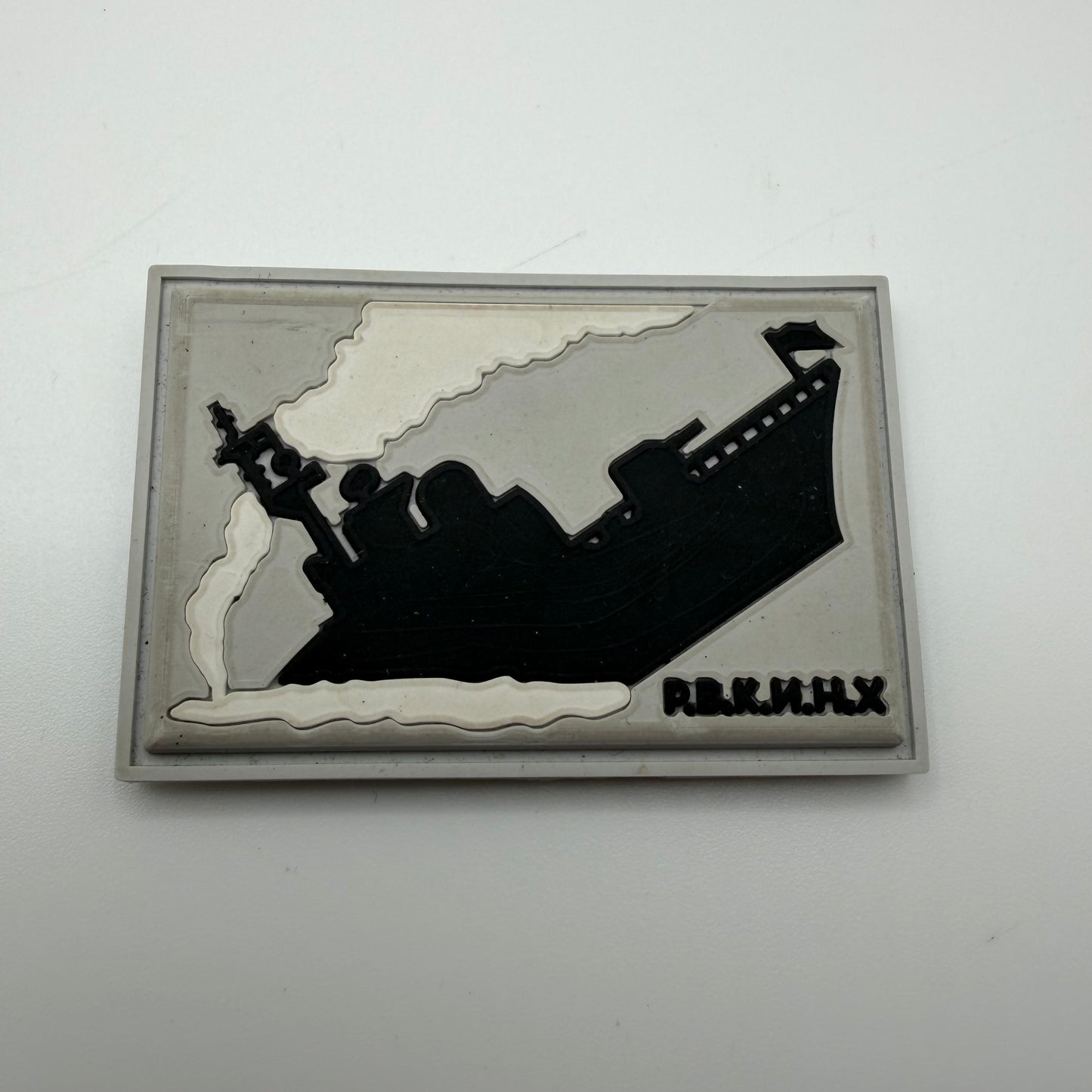 Decorative patch with a black silhouette of a ship on a white background