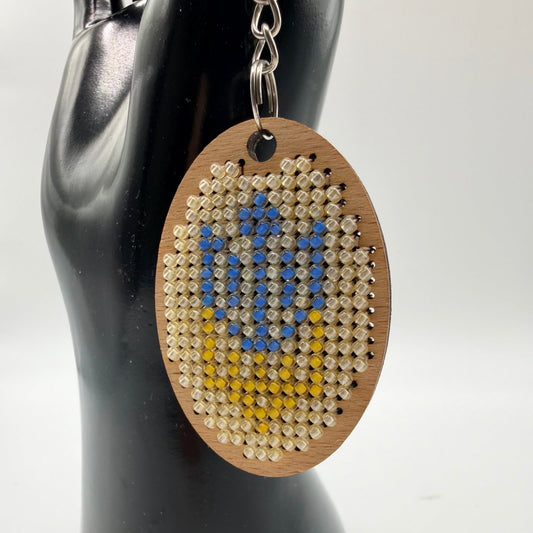 Wooden keychain with bead design on a mannequin arm against a white background