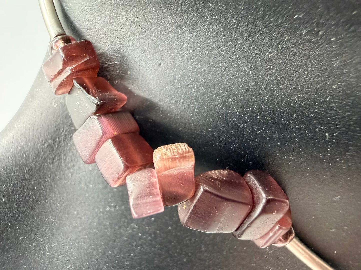 Close-up of a beaded necklace with pink and red beads on a dark background