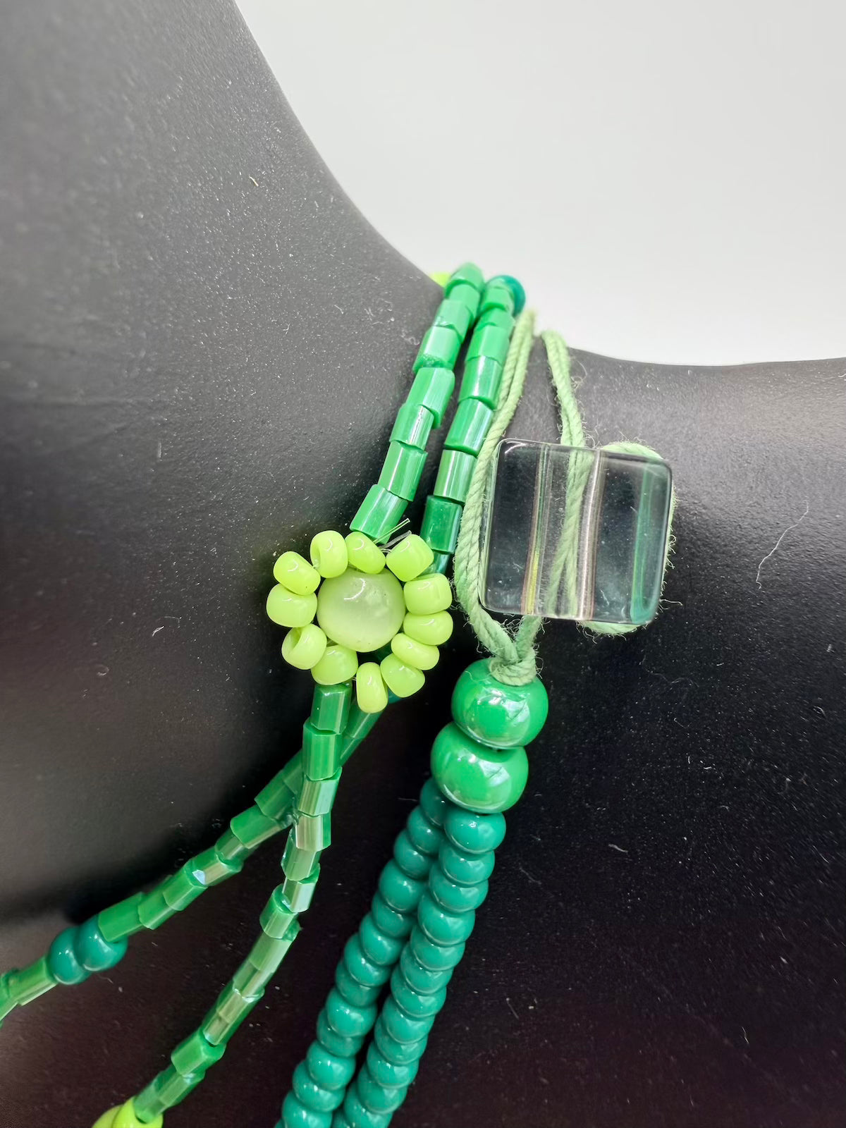 Green beaded bracelet with a clear crystal clasp on a black surface