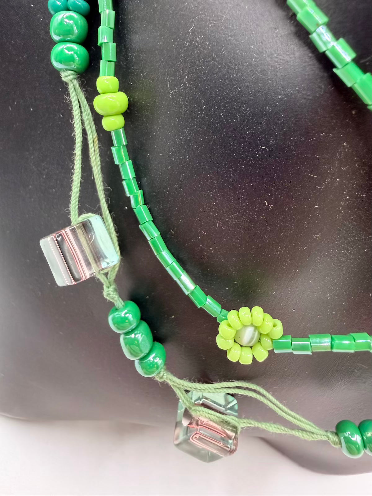 Green beaded necklace with a silver clasp on a dark background